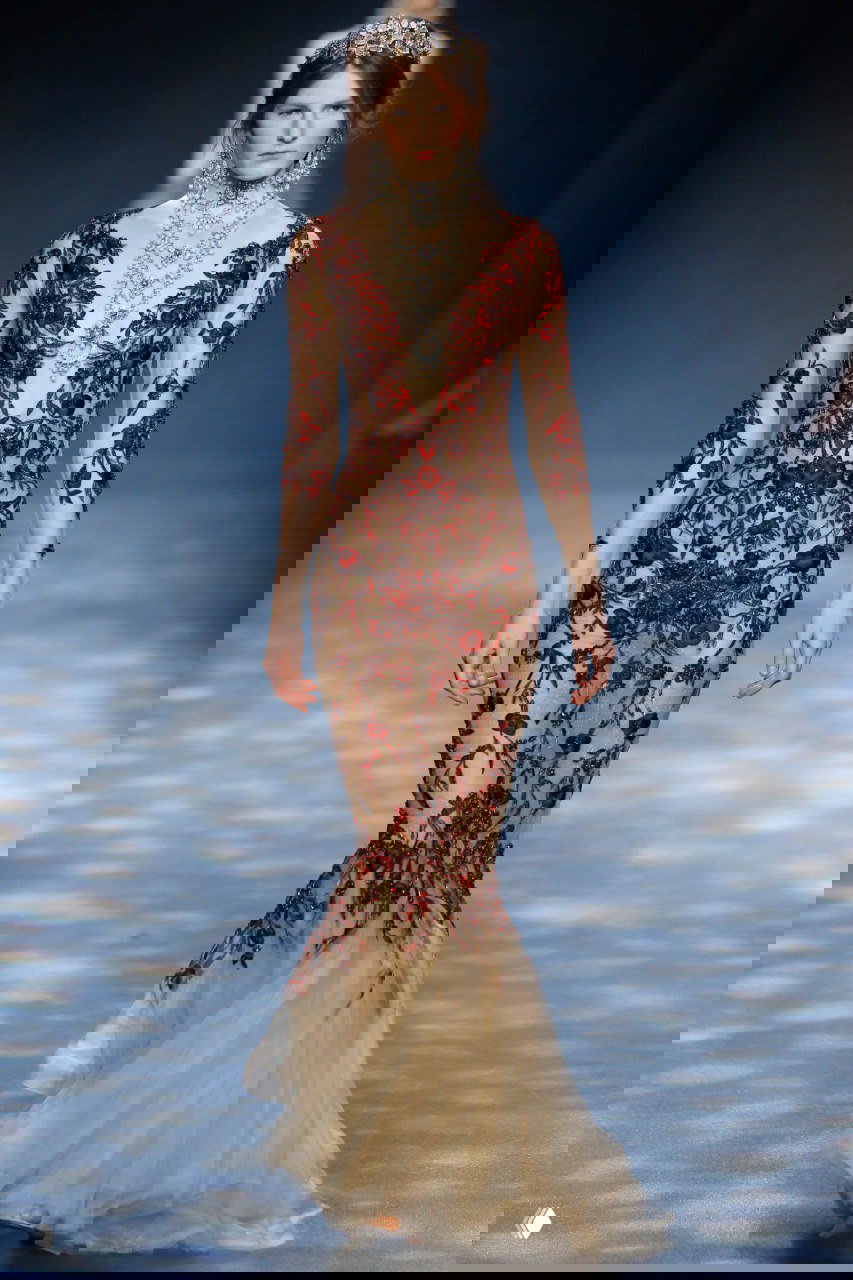 Приталенное платье‑русалка Marchesa с нюдовой сеткой и насыщенной красной вышивкой, создающей эффект тонкой скульптуры на фигуре.