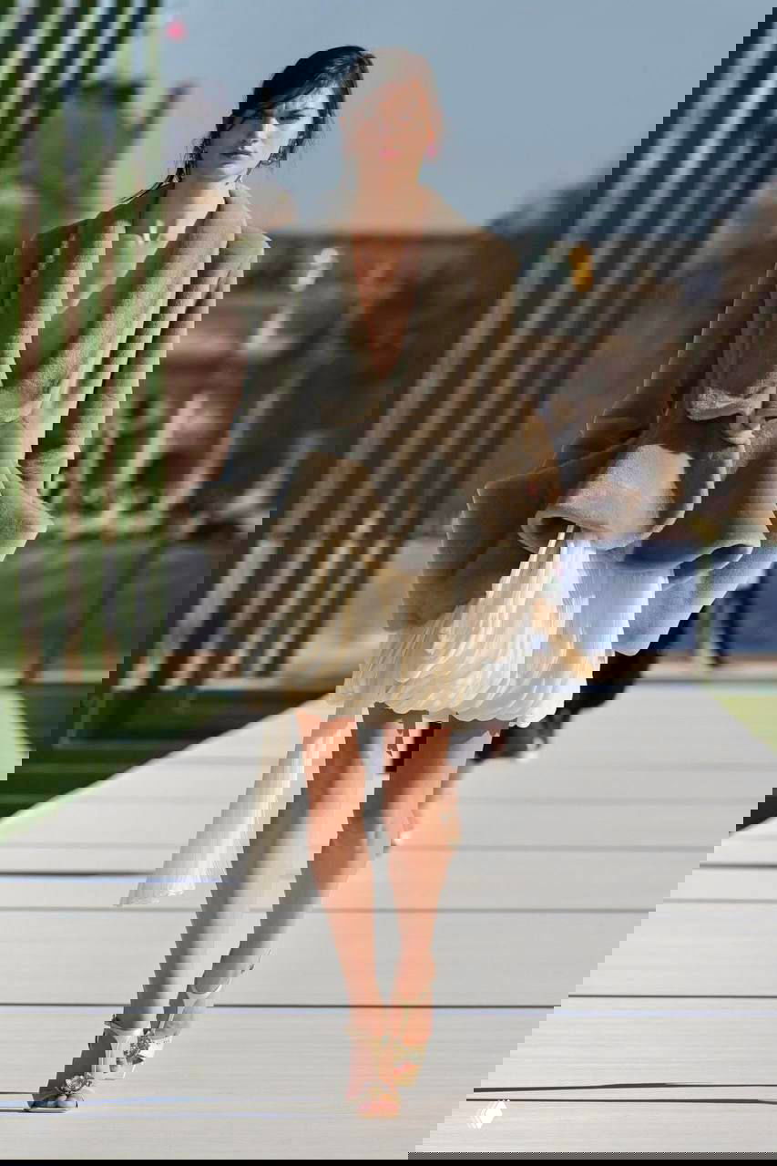 Модель в объемном пальто и воздушной юбке идёт по подиуму; кадр передаёт контраст фактур и игру пропорций в коллекции Джонатана Андерсона.