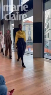 Миланский показ: модели в коллекции SA SU PHI идут по подиуму в помещении с большими окнами и заметным логотипом Marie Claire на фоне.