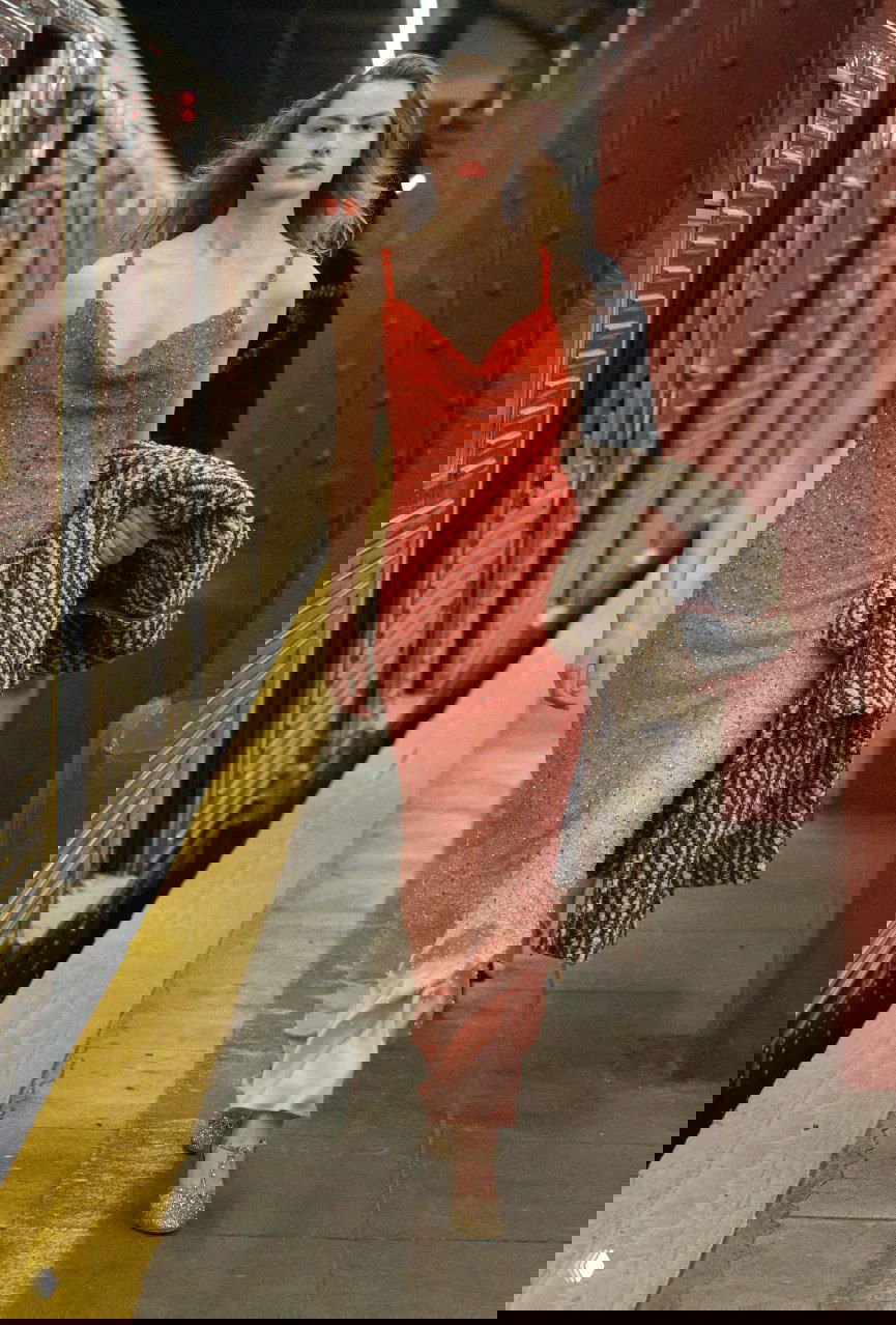 Модель в переливающемся розово‑красном платье с эффектом градиента идёт по платформе нью‑йоркского метро в рамках показа Матье Блази для Chanel.