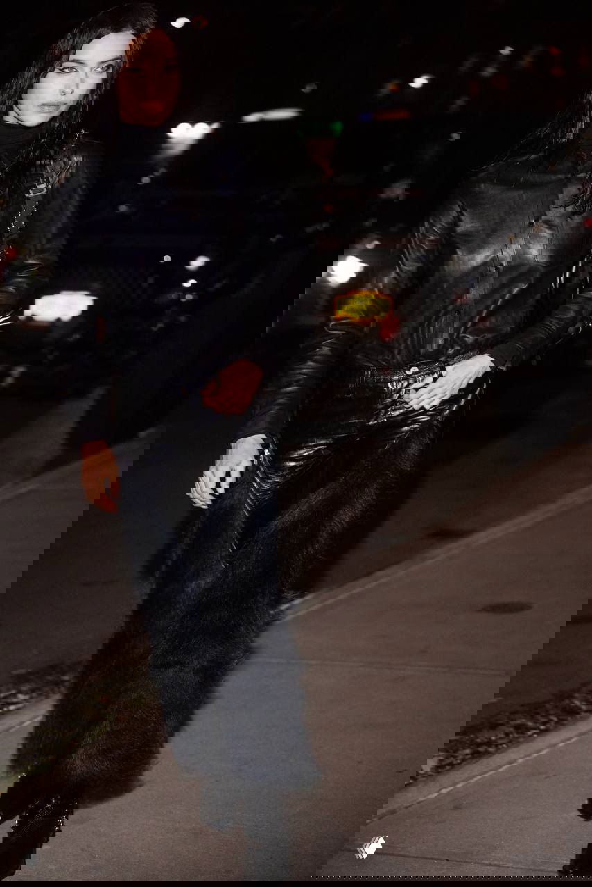 Папарацци‑кадр: длинные кожаные брюки и рубашка чёрного цвета с фактурными элементами, прогулка по ночному городу.