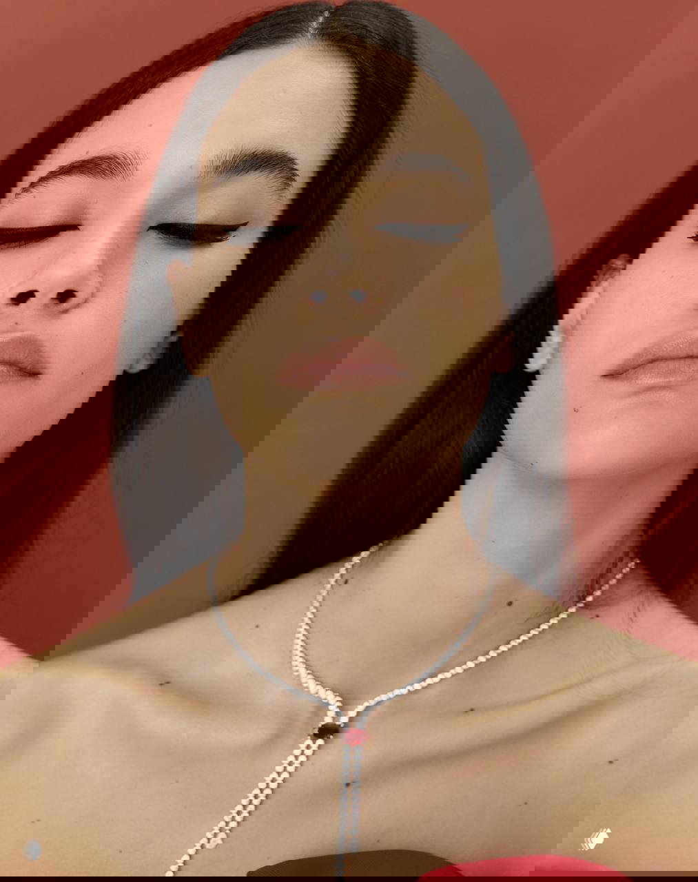 Крупный план лица модели с идеальной стрелкой на веках и ожерельем: демонстрация работы визажиста — графичный макияж и аккуратная укладка волос.