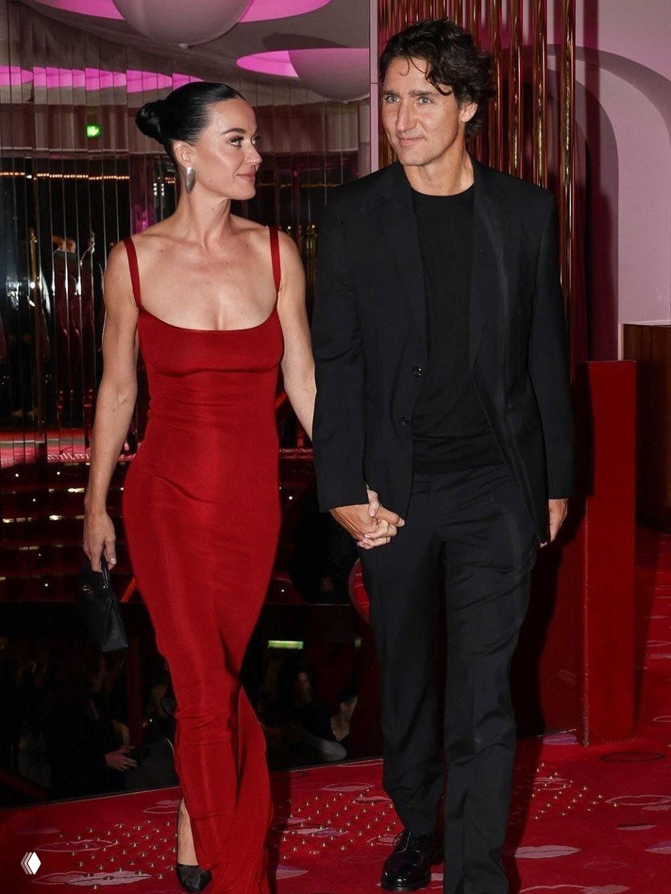 Пара в клубе Crazy Horse в Париже на красной сцене: женщина в красном платье и мужчина в тёмном костюме идут вместе по красной дорожке.