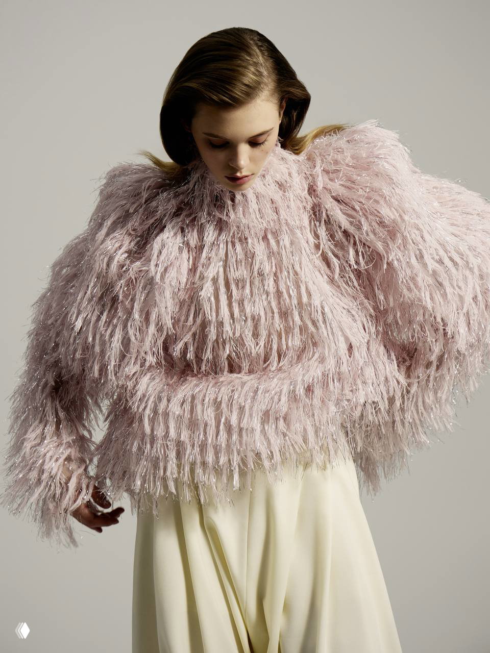 Модель в пуховом розовом свитере с текстурой перьев на нейтральном фоне: игра объема и фактуры в образе съемки для журнала.