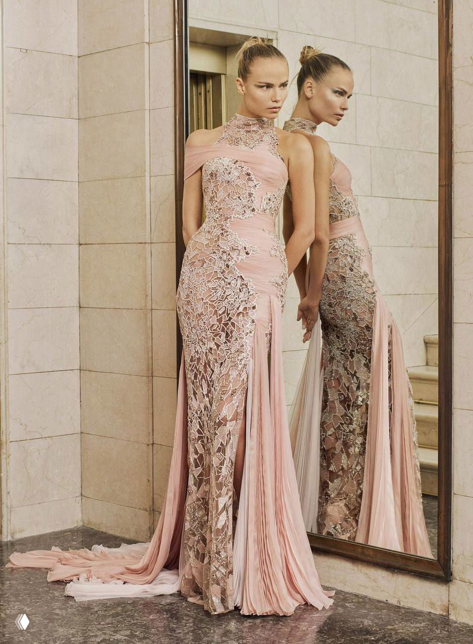 Модель в светло-розовом облегающем платье с вышивкой и плиссировкой стоит рядом с зеркалом — романтическая эстетика кампейна Atelier Versace.