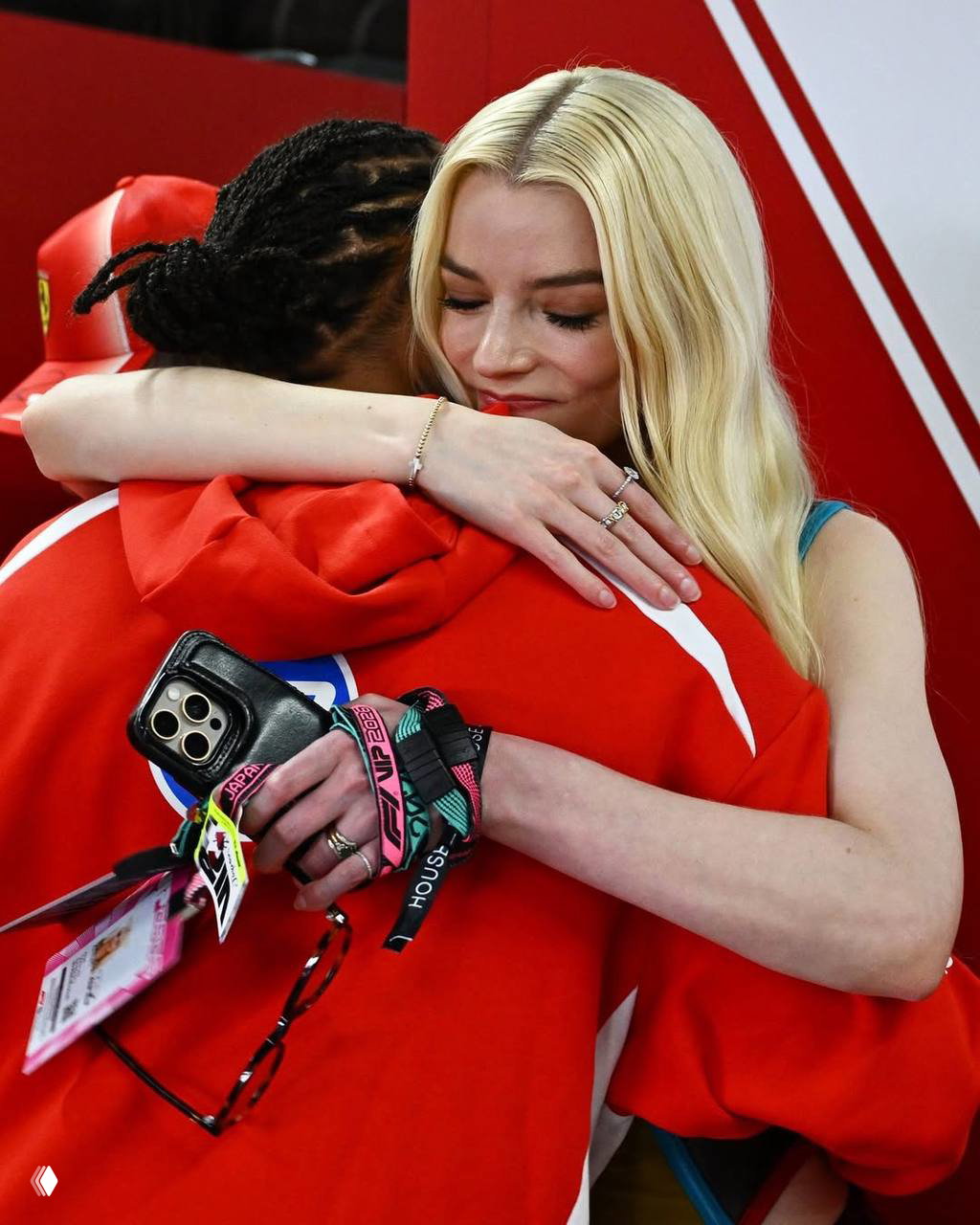 Тёплое объятие между двумя приглашёнными на трассе, на заднем плане видны пропуска и браслеты доступа мероприятия