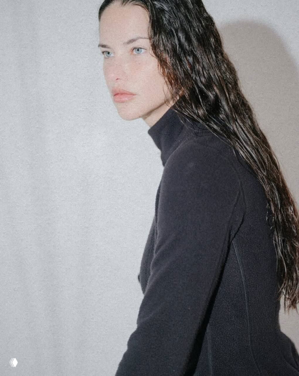 Профильный портрет модели с влажной укладкой и тёмным водолазочным свитером на нейтральном фоне; спокойный взгляд в сторону.