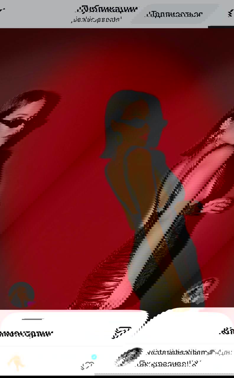 Джеки Апостел на красном фоне в эффектном платье и чёрных очках — скриншот из Instagram, рядом видно сердце и комментарий Виктории.