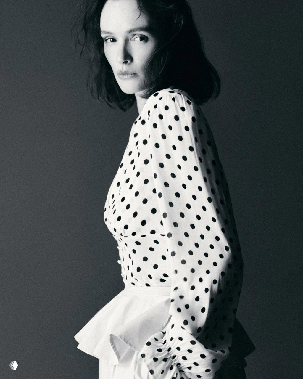 Чёрно‑белый профильный портрет: модель в платье в горох с пышной баской, контраст светотени подчёркивает силуэт и фактуру ткани.