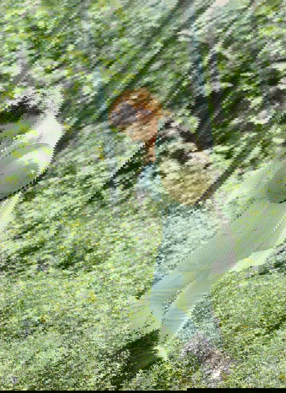 Женщина-модель в светлом наряде и панамке идёт по зелёному лугу среди берёз — атмосферный винтажный кадр модной съёмки для журнала, 1994.