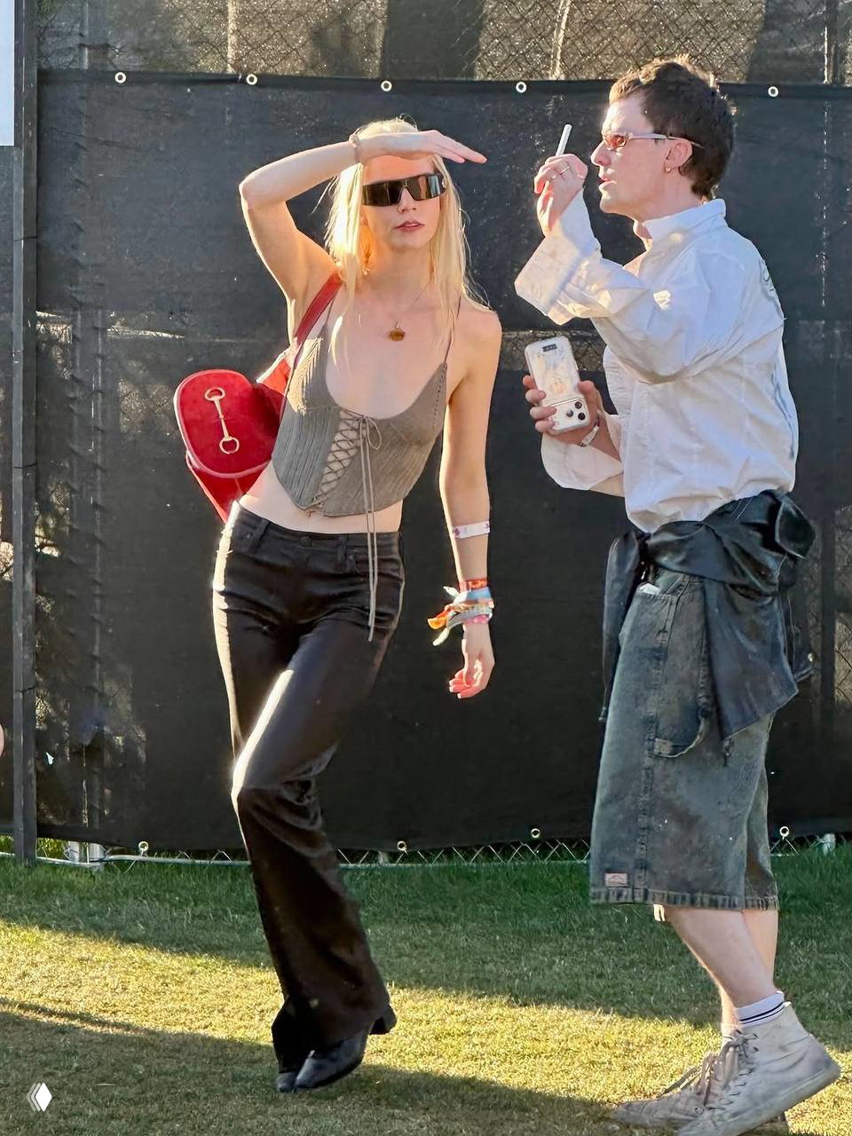 Женщина в корсетном топе и кожаных брюках с аксессуарами и браслетами на дневной территории фестиваля Coachella — смелый летний образ.