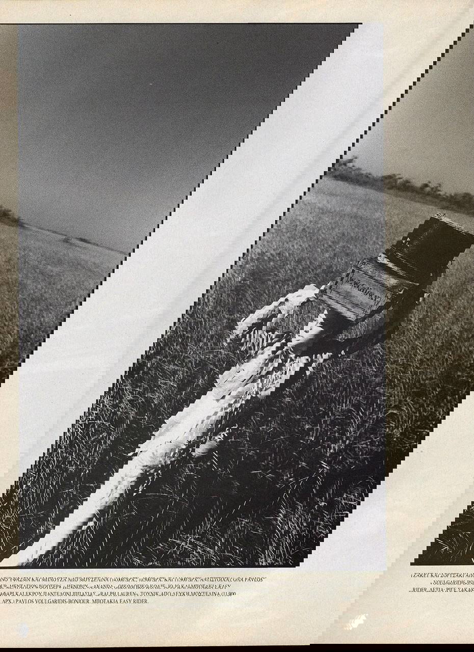 Чёрно-белый снимок: женщина несёт чемодан по высокому травяному полю, романтичный винтажный образ в редакционной фотосессии 1994 года.