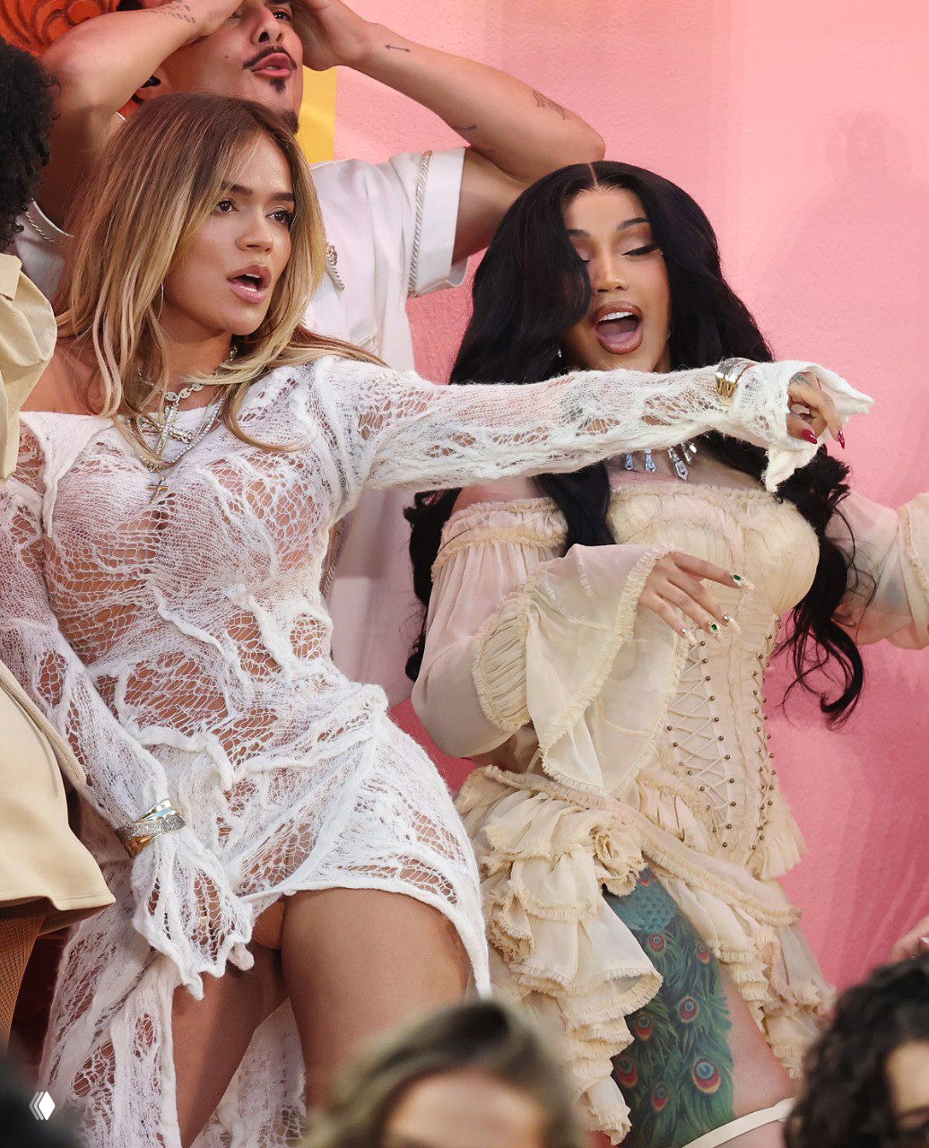 Две артистки в светлых платьях танцуют на сцене; кадр показывает энергичный момент выступления и близкие планы артистов и фонового декора