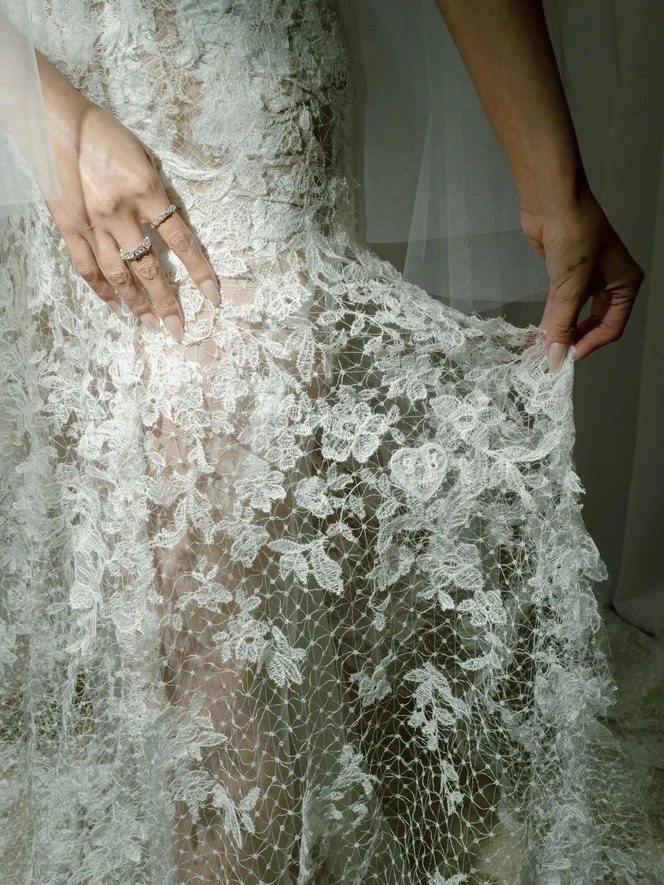 Крупный план рук в кружевном свадебном платье: длинные мягкие нюд‑ногти с тонкой хромовой втиркой и глянцевым топом, подчёркивающие свадебный образ.