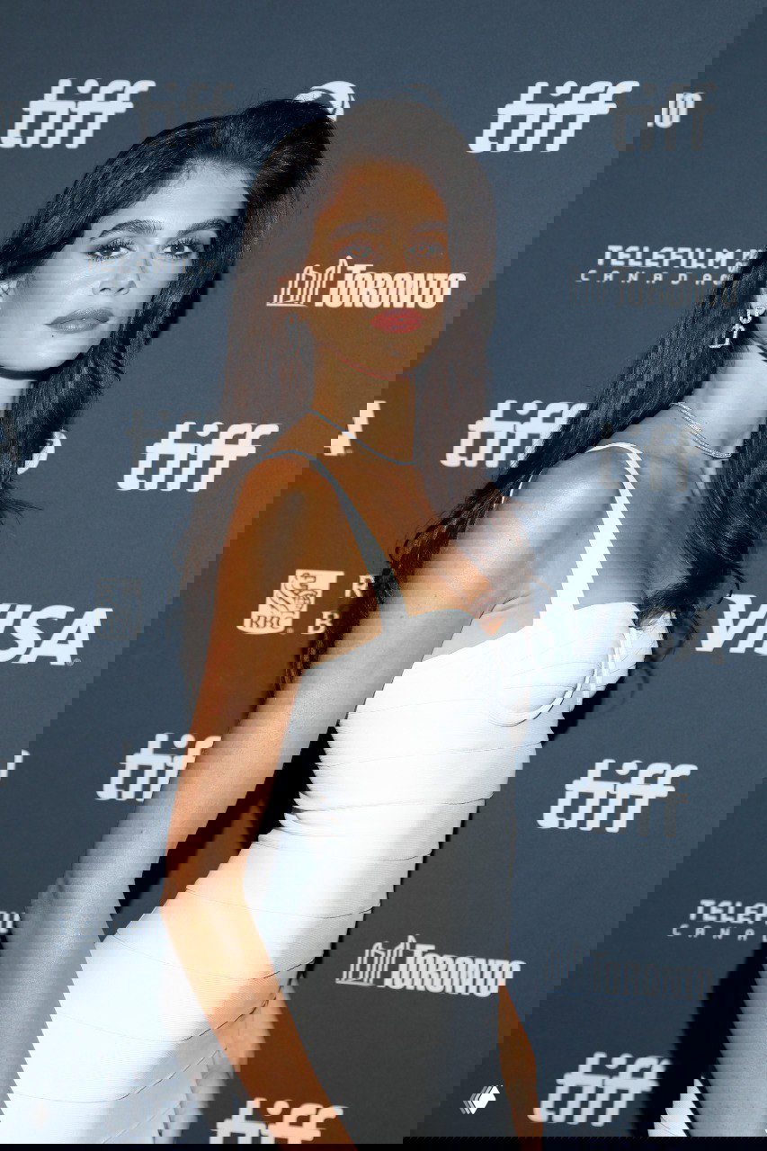 Модель на красной дорожке в белом плотном бандажном платье; крой подчёркивает талию и подчёркнутый силуэт в вечернем образе.