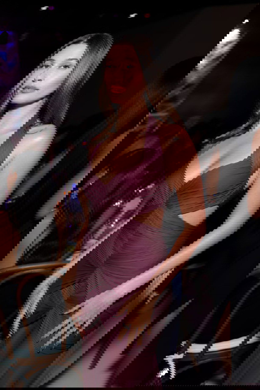 Знаменитость в тёмно-бордовом бандажном платье с драпировкой на светском мероприятии; подчёркнутый силуэт и вечерний шик.