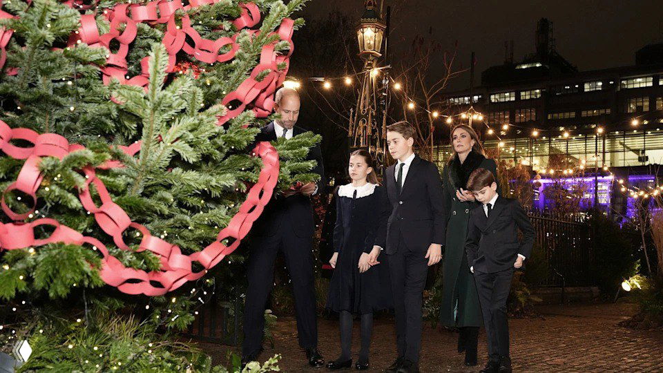 Женщина и девочка идут рядом друг с другом по мощёной дорожке в окружении праздничных декораций и огней