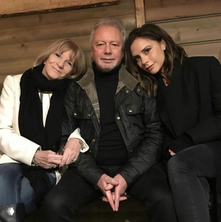 Семейный групповой снимок: Жаклин Адамс, супруг и Виктория Бекхэм сидят рядом в неформальной обстановке — спокойный уютный кадр.