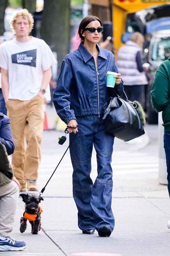 Деним‑лук в духе 90-х: джинсовый костюм, сумка через плечо и стакан кофе в руке во время прогулки по городу.