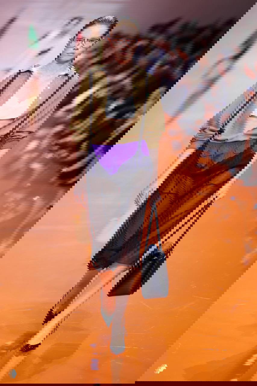 Полупрозрачная юбка и открытая рубашка на модели, сочетание просвечивающих материалов и спортивных деталей в образе сезона.