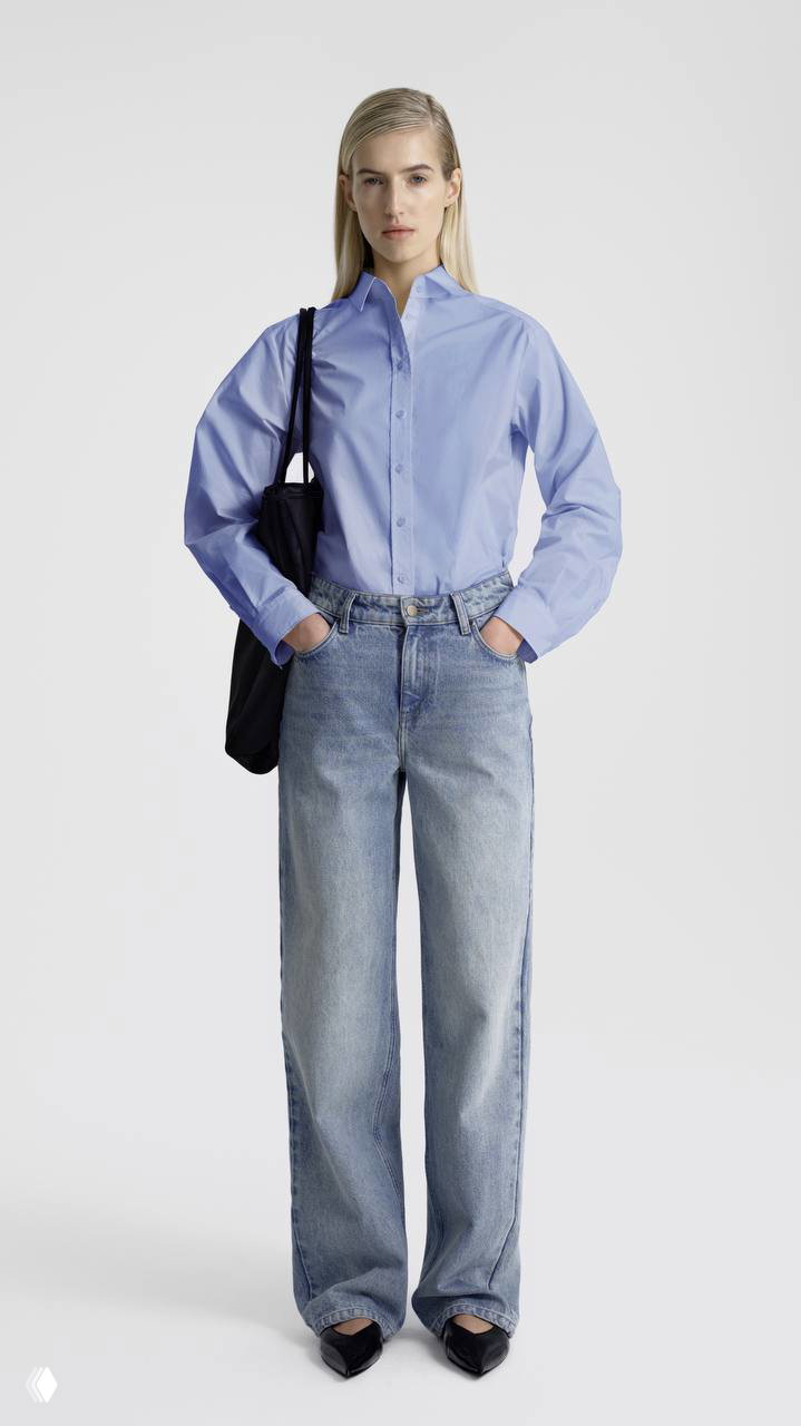 Модель в небесно‑голубой рубашке и широких джинсах: дневной, непринужденный образ в сочетании с продуманной посадкой и лаконичностью силуэта.