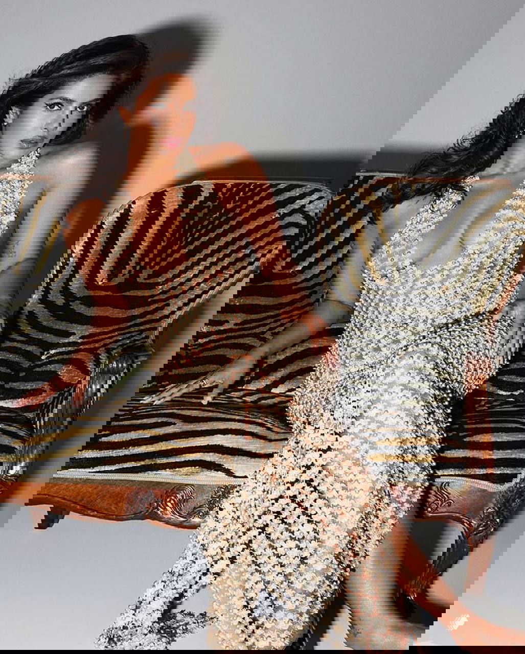 Женщина в прозрачном платье с блестящими аппликациями сидит на диване с зебровым принтом; интерьерный кадр из журнальной съёмки для Variety.