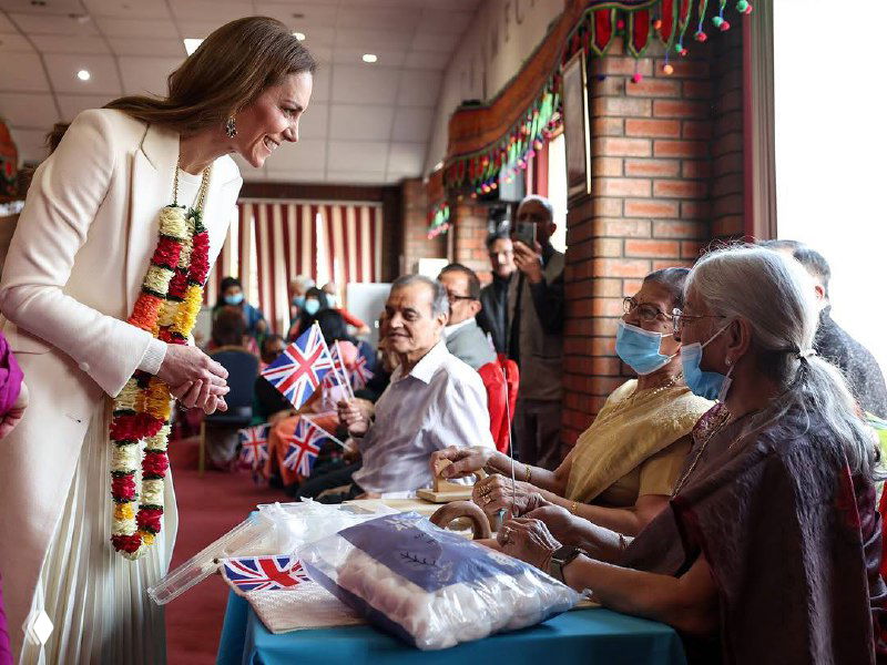 Группа людей в выставочном зале, женские наряды и демонстрационные элементы экспозиции; снимок с артефактами и цифровыми искажениями.