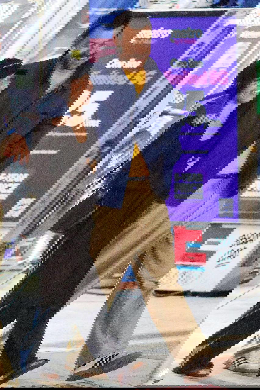 Крупный кадр пары в городском свете: Зои в тёмной шапочке и кепке, Гарри улыбается в паре синих и бежевых вещей — непринуждённая уличная эстетика пары.