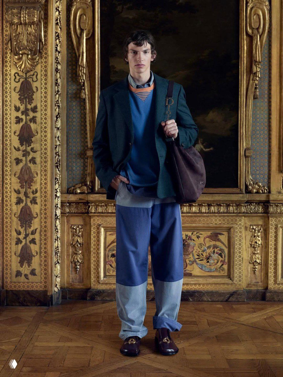 Модель в светлых мешковатых брюках и тёмном пиджаке с классической рубашкой, кадр подчёркивает академическую атмосферу съёмки в интерьере парижского особняка.