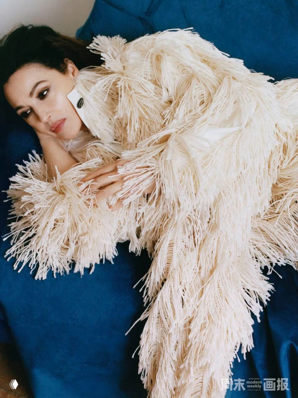 Крупный план на расслабленную позу: женщина в пушистом фактурном пальто лежит на диване, подчёркнута текстура одежды и задумчивое выражение лица.