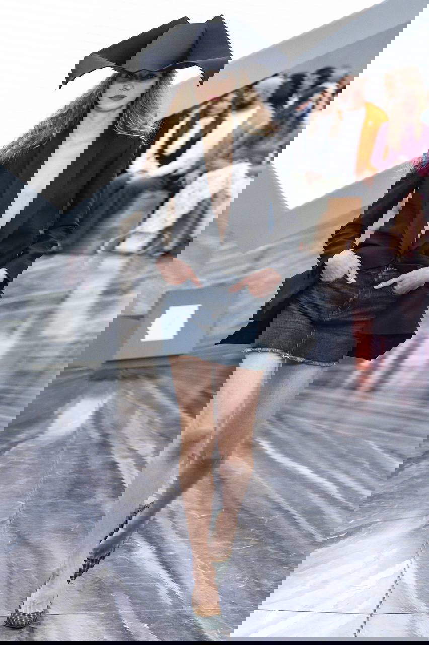 Чёрный жакет с большой эксцентричной шляпой и джинсовой мини‑юбкой, акцент на головные уборы как ключевой аксессуар сезона.