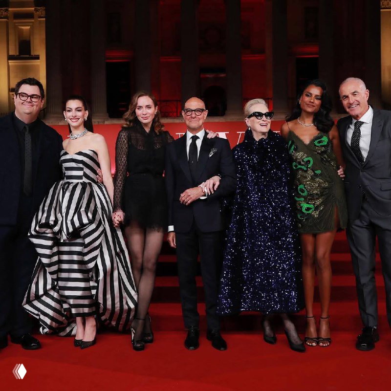 Группа актёров в вечерних нарядах на ночном гала-приёме у Национальной галереи: блестящие платья, строгие костюмы и красная ковровая дорожка.