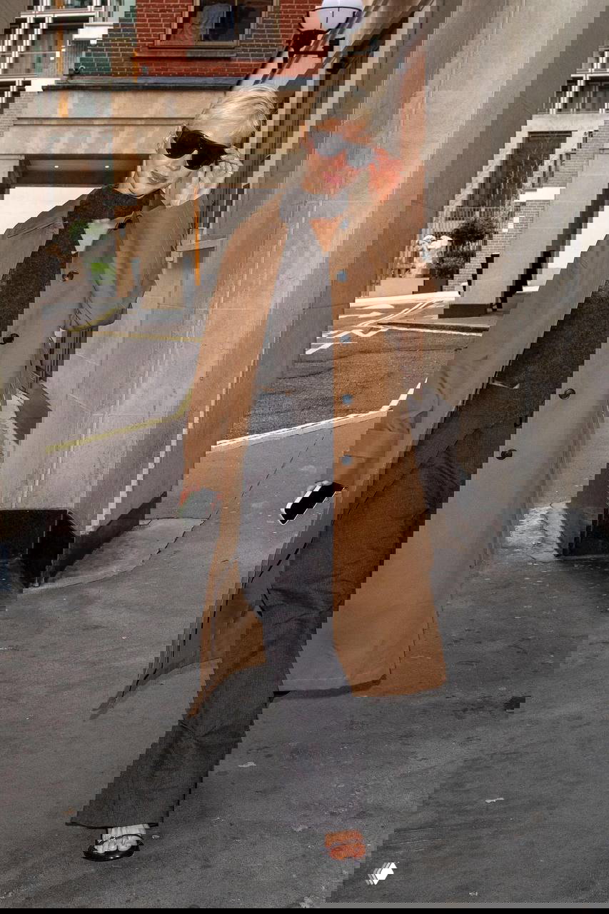 Женщина в длинном платье демонстрирует гладкую укладку с короткими прядями у лица и лёгкими слоями на длине для воздушного эффекта.