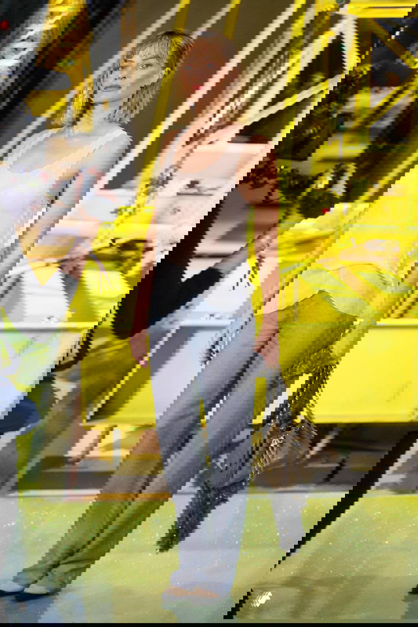 Уличный кадр с короткой блондинистой стрижкой, строгий повседневный образ с пальто и солнечными очками, подчёркнутая текстура волос.