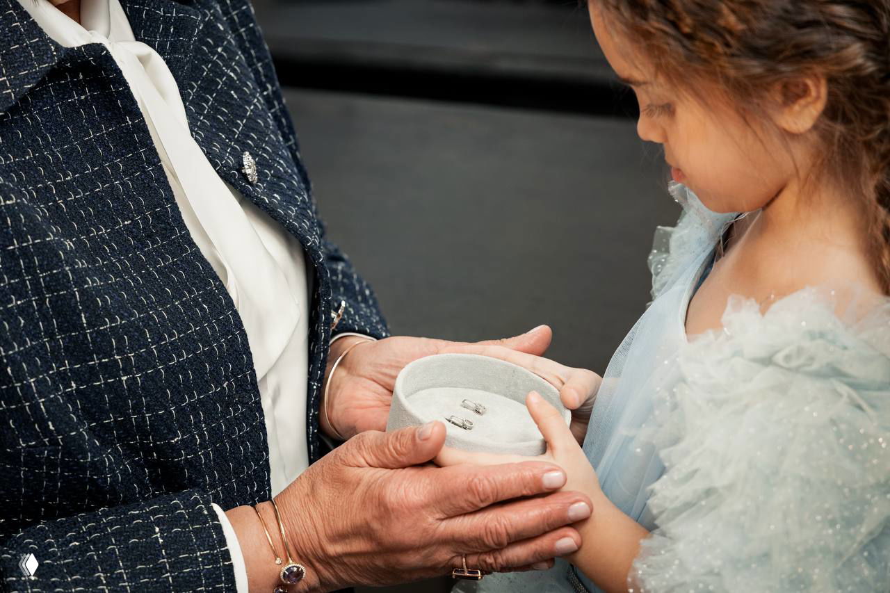 Руки Татьяны Овечкиной передают шкатулку с ювелирными изделиями маленькой девочке — момент семейной традиции и передачи ценностей.