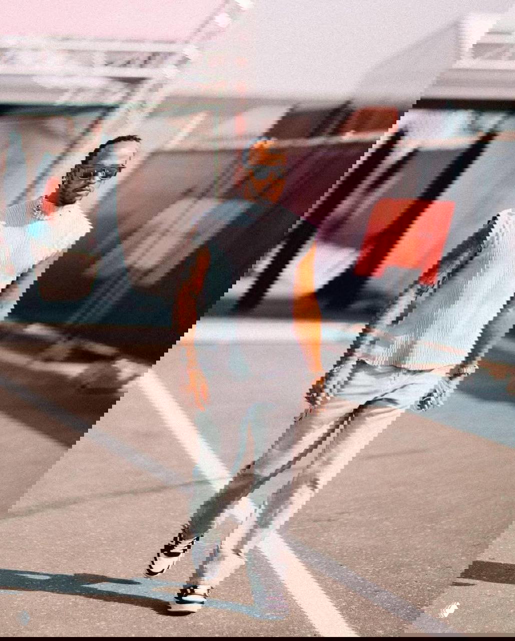 Льюис Хэмилтон в повседневном аутфите на трассе: светлый жилет и свободные брюки; уличный стиль гонщика вне болида.