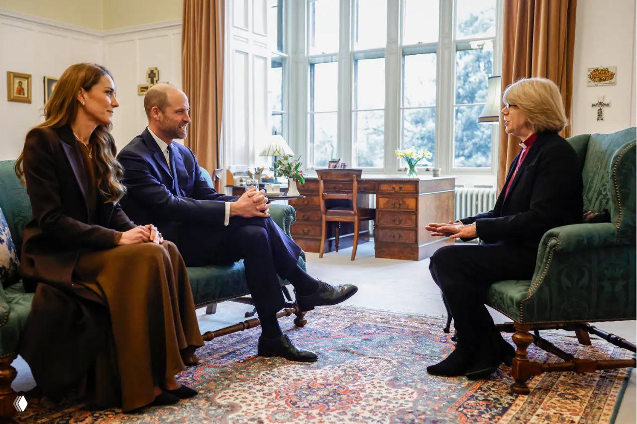 Женщина и мужчина сидят на диване напротив пожилой служительницы в светлой комнате; вокруг письменный стол, вазы и ковёр создают домашнюю атмосферу.