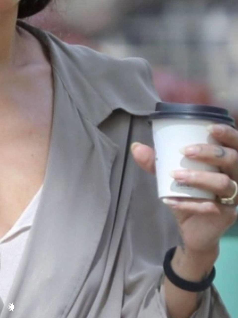 Крупный кадр руки с бумажным стаканом кофе, на безымянном пальце видно кольцо — деталь, привлекшая внимание папарацци и фанатов.