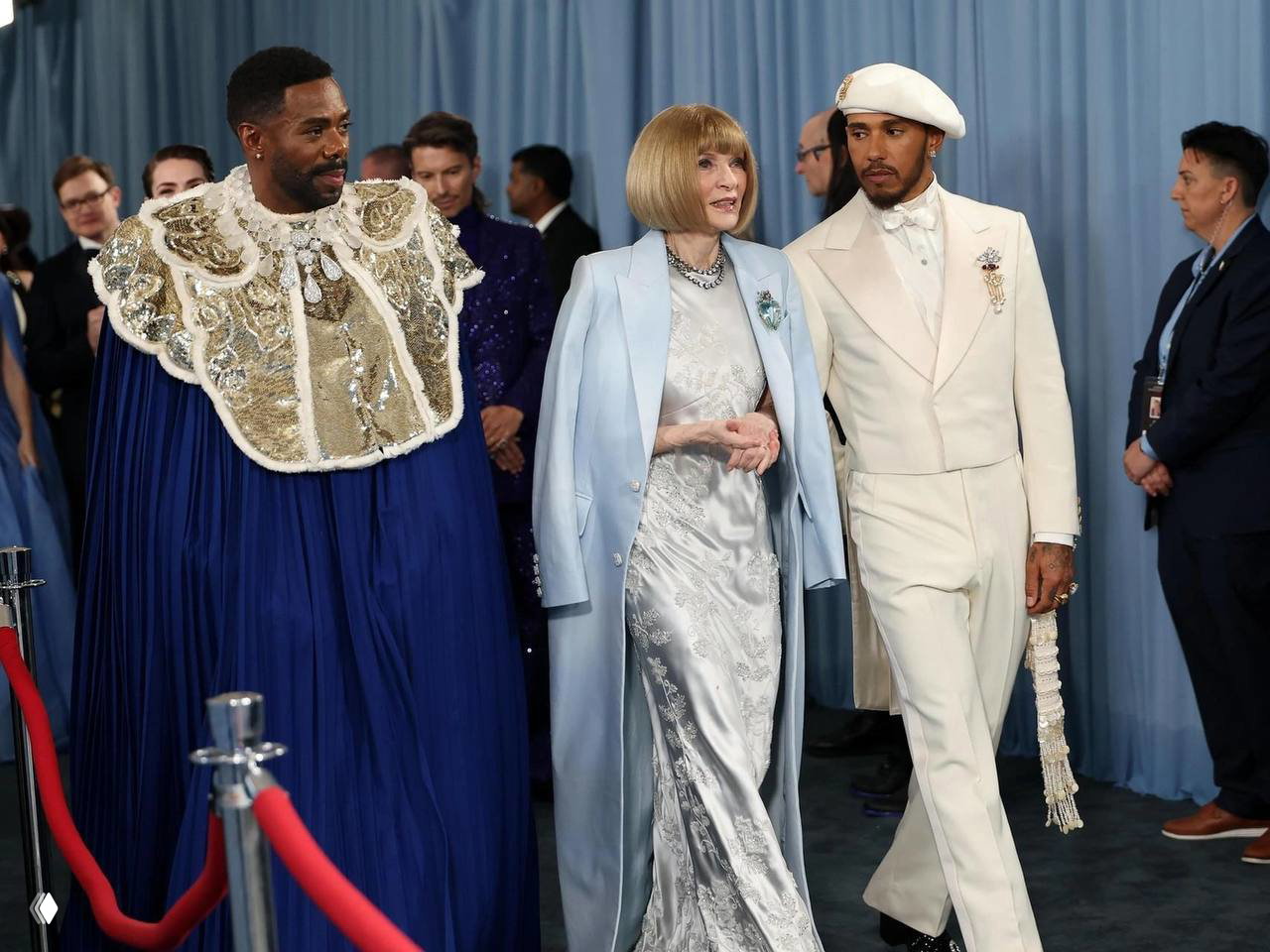 Льюис Хэмилтон рядом с Анной Винтур в светлом костюме и беретом; официальный выход на Met Gala с элегантным ретро‑акцентом.