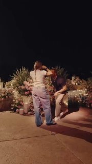 Момент на открытом воздухе: предложение или романтическая сцена с цветами и свечами, где мужчина делает женщине неожиданный жест.