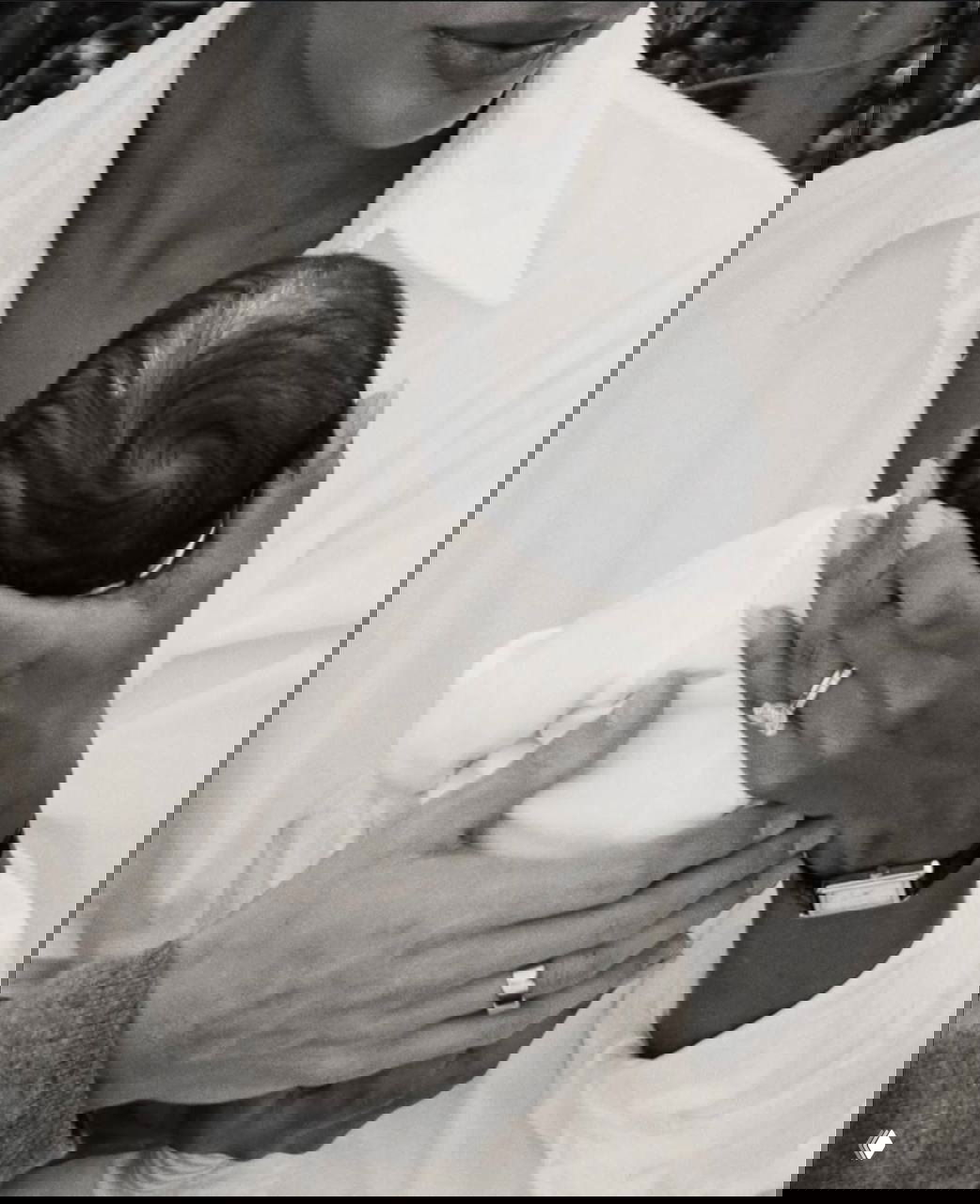 Крупный план: руки родителей поддерживают голову и тело новорождённого Матео Айра Борреро в чёрно‑белом кадре, видны кольца и детали ухода.