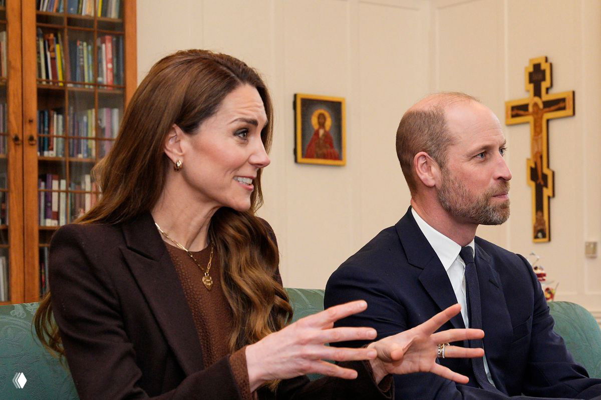 Профильная фотография: женщина в шоколадном платье жестикулирует во время разговора рядом с мужчиной в костюме на фоне книжных полок и религиозных икон.