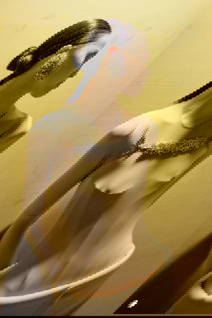 Профиль модели с крупной декоративной серьгой и минималистичным нарядом — сочетание монументальных украшений и спокойной одежды для контраста.