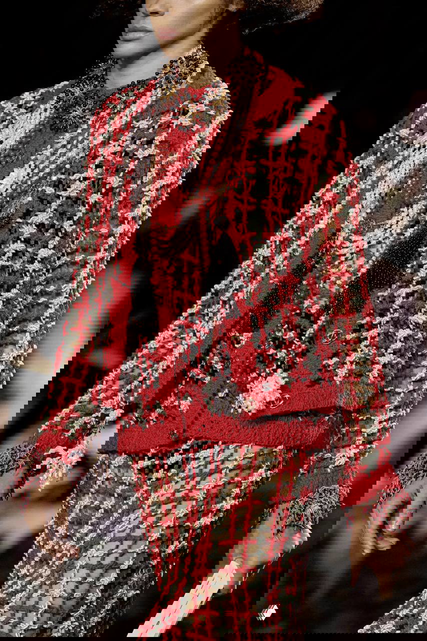 Подиумный образ с многоярусными ожерельями и красным жакетом вязаной фактуры — многослойность и богатая отделка в одном образе.