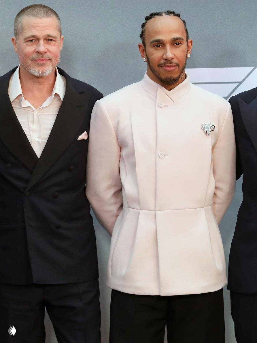 Льюис Хэмилтон в светлом пальто на премьере рядом с Брэдом Питтом; официальный фотоколл и сдержанный вечерний стиль.