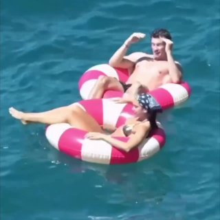 Мужчина и женщина на надувных кругах в море, спокойная голубая вода и летняя атмосфера отдыха на побережье Амальфи в районе Салерно.
