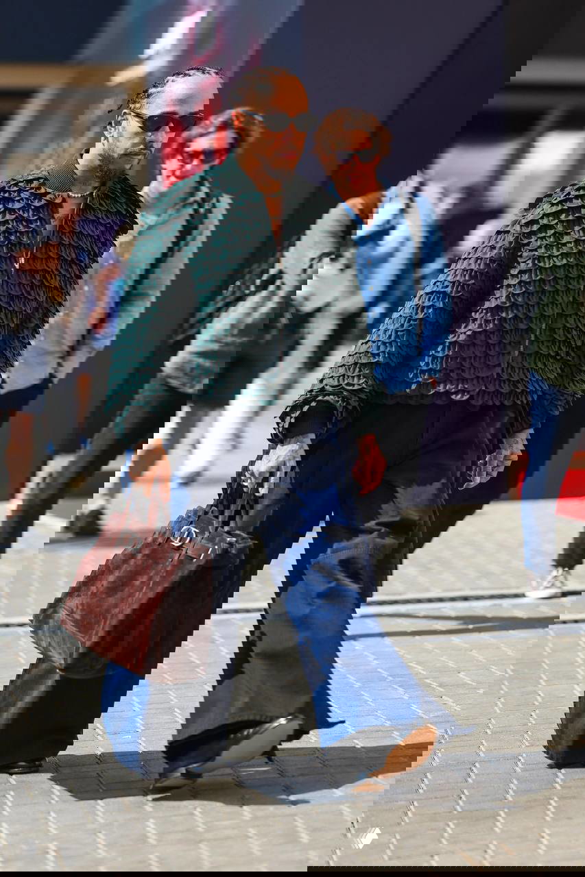 Льюис Хэмилтон в зелёной фактурной куртке и широких брюках с сумкой Dior; уличный стиль с акцентом на текстуру и бренды.