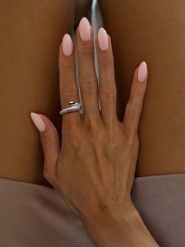 Рука с молочно-розовым маникюром овальной формы на фоне кофейной чашки и блокнота; мягкий, офисно-повседневный оттенок.