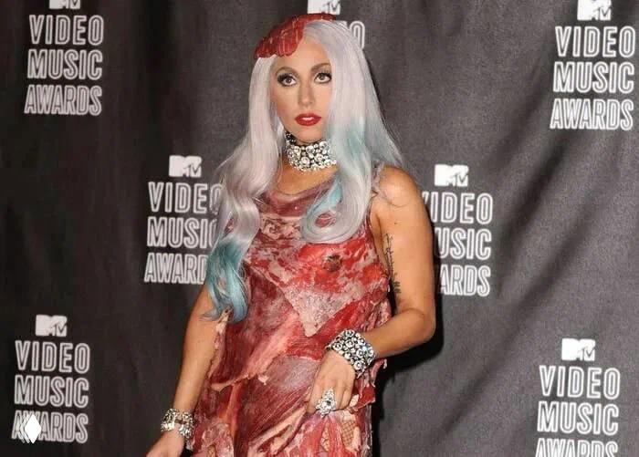 Ретро‑фото с красной ковровой дорожки: женщина в платье, имитирующем мясную текстуру, узнаваемый провокационный сценический образ в стиле ранних премий.