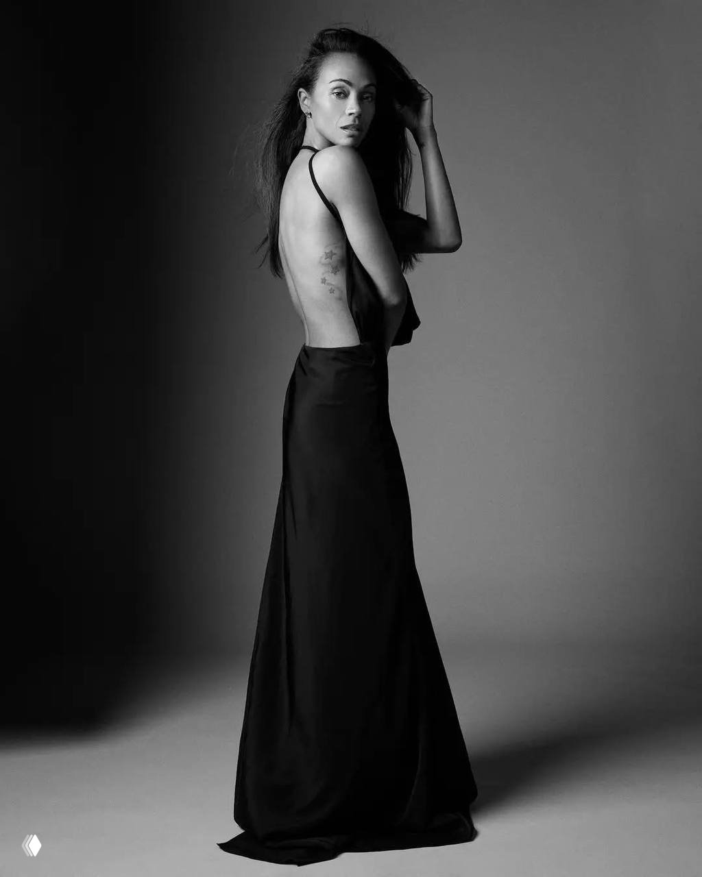 Черно‑белая студийная фотография женщины в длинном платье с обнаженной спиной, силуэтная композиция и художественное освещение.